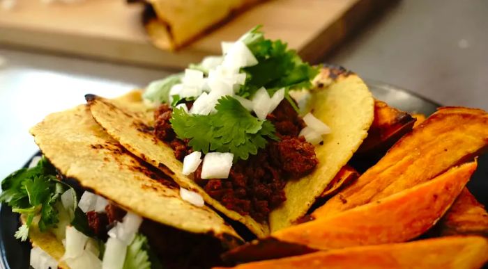 Easy chorizo street tacos topped with cilantro and onions, served with roasted sweet potato wedges