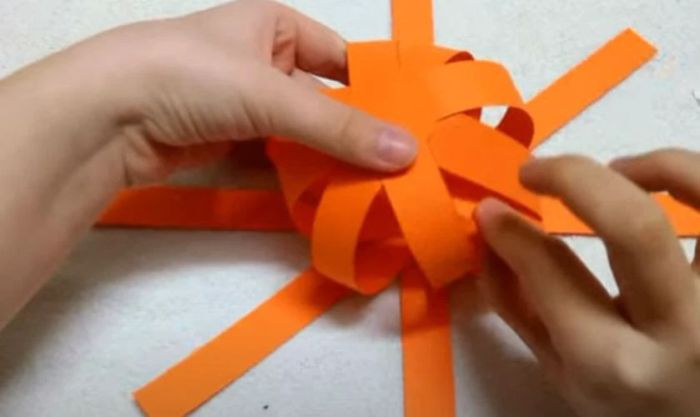 Tạo hình quả bí ngô bằng cách dán và chồng các dải giấy lên nhau