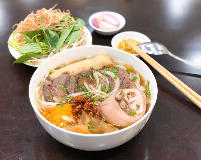 A photo of Bún Bò Gốc Huế O Tú, showcasing the mouthwatering bowl of Huế beef noodle soup that draws in so many loyal customers.