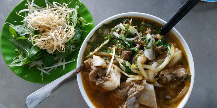 A photo of Bún bò Cô Mai, showcasing a steaming bowl of flavorful beef noodle soup, garnished with fresh herbs and served with colorful vegetables.