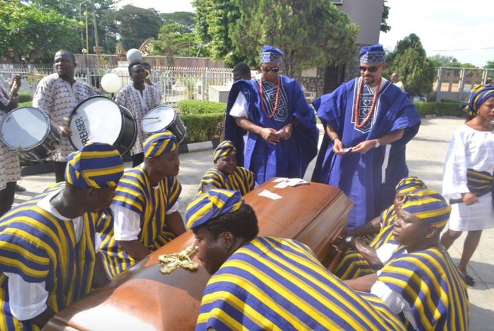 Just before my father’s funeral, Mike, my husband (left), and Femi, my brother, placed money on the coffin, a gesture of respect.
