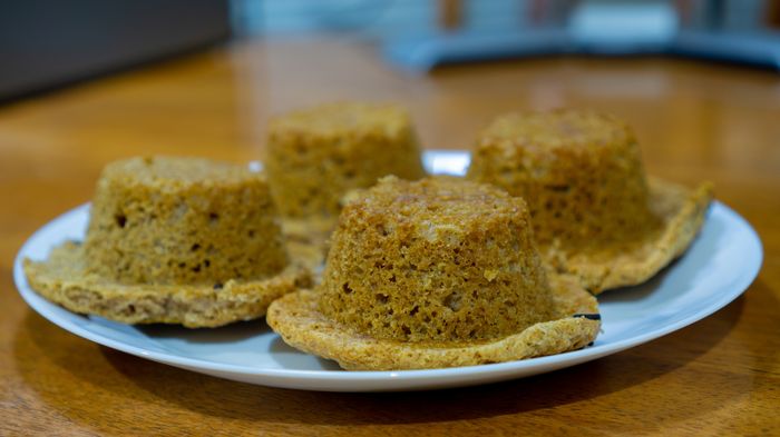 Mini bundt cakes arranged on a white plate, featuring flat tops and slightly raised edges that look like tiny hats