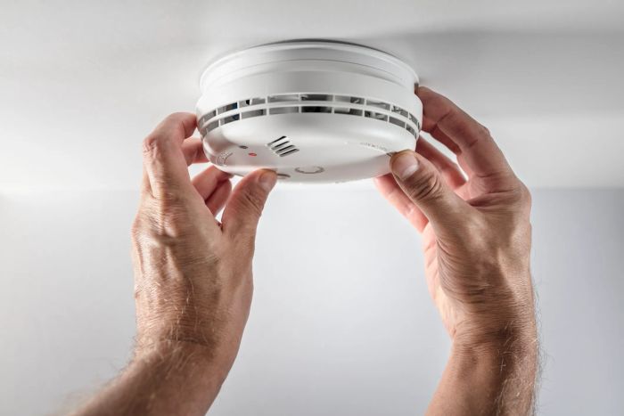 A person is installing a smoke detector on the ceiling as a safety measure.