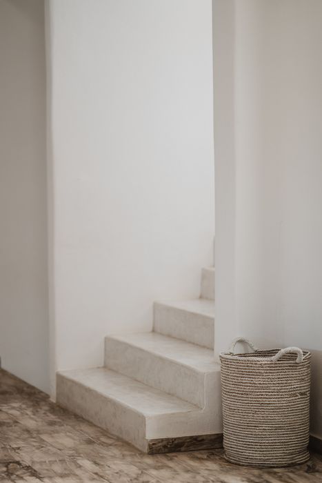 A modern staircase with a woven basket placed on the floor nearby