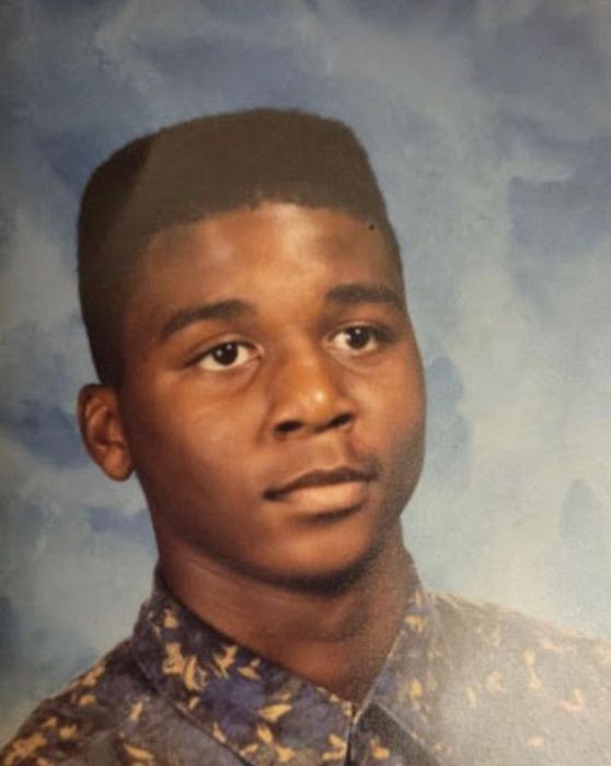A young individual in a studio portrait, wearing a patterned shirt and gazing slightly past the camera.