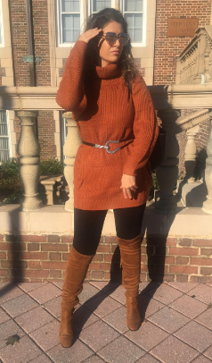 Reviewer posing in a dark orange sweater dress paired with black leggings, brown knee-high boots, and sunglasses