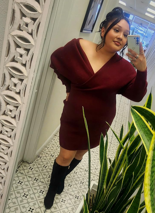 Reviewer wearing a burgundy off-shoulder form-fitting dress paired with boots