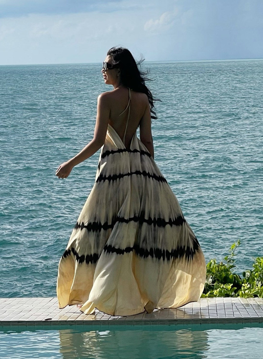 A model wearing a tie-dye white and black maxi dress with a backless halter design