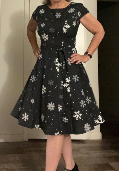 A person indoors, wearing a short-sleeved dress adorned with snowflake patterns