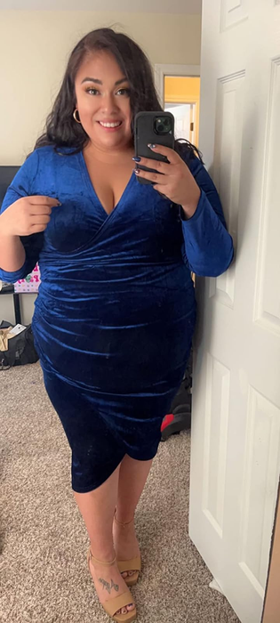 A person in a velvet wrap dress taking a mirror selfie at home