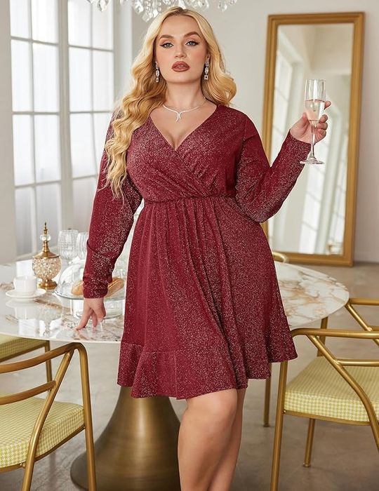 A model in a flowing red dress holds a glass, standing near a table set with glassware