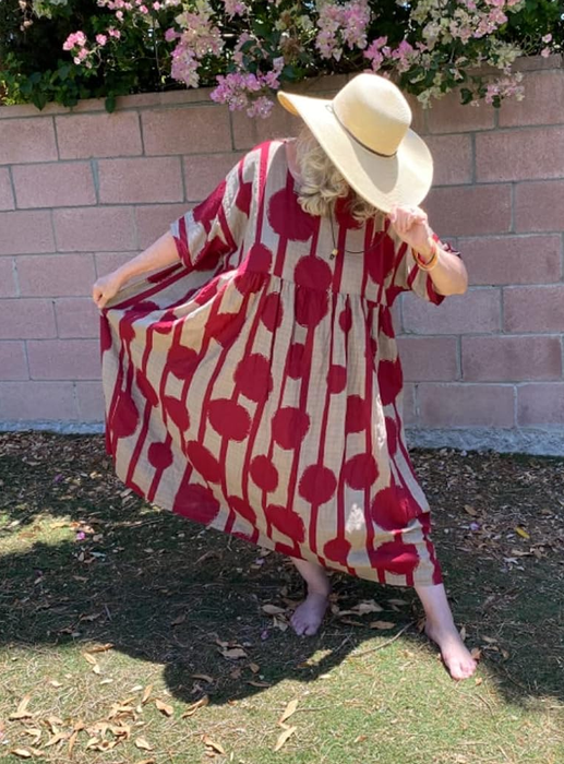 reviewer wearing a red polka dot and striped sleeved dress that falls just above the ankle