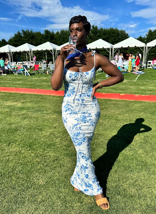 reviewer wearing a white dress adorned with blue flowers