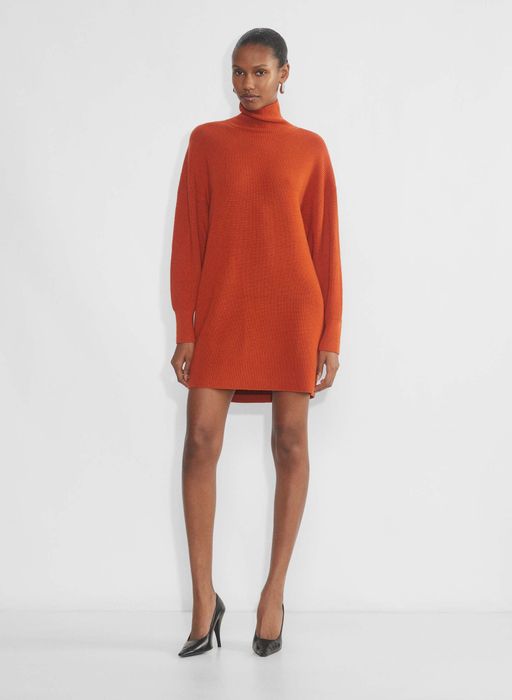 Dressed in a striking red, high-neck sweater dress complemented by sleek black heels, this outfit is ideal for a day of fashion-forward shopping.