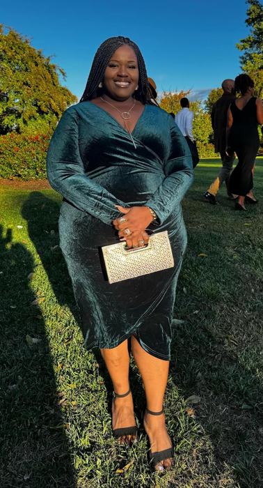 A person wearing an elegant velvet dress and holding a stylish handbag at an outdoor event