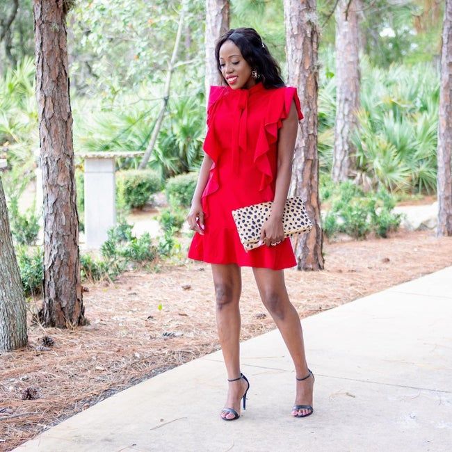 A reviewer models a vibrant red ruffle dress, exuding charm and elegance.