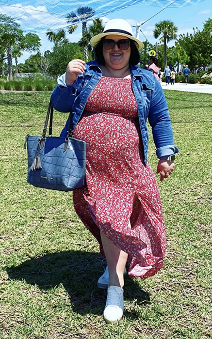 reviewer wearing the red dress paired with a denim jacket