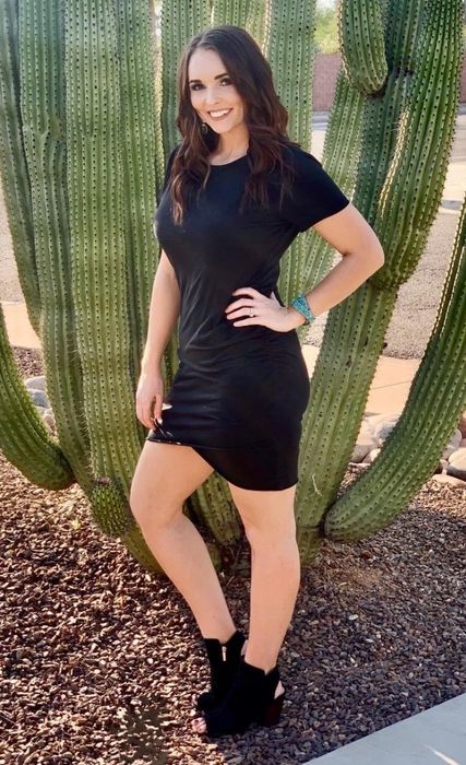 reviewer wearing a black dress posing in front of a cactus
