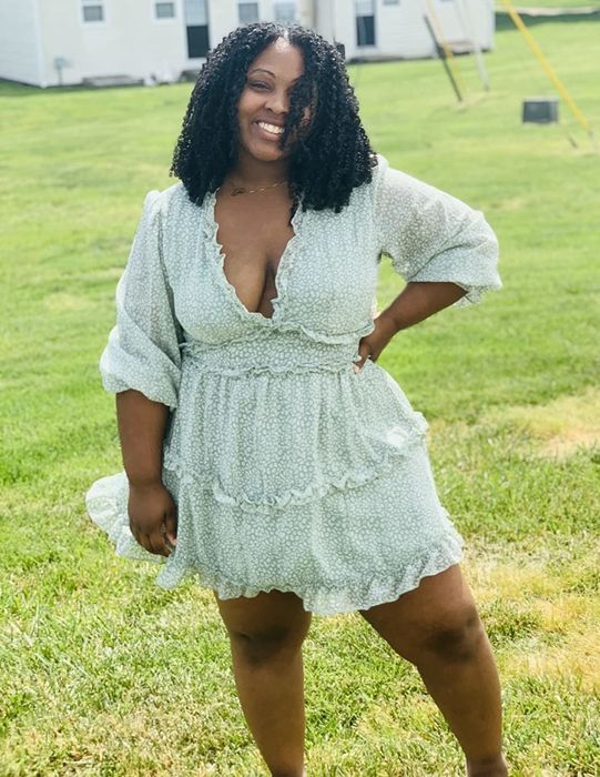 A reviewer wearing a long-sleeve green ruffle dress