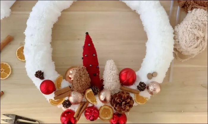 Tổ chức và gắn các phụ kiện trang trí quanh vòng nguyệt quế bằng keo để chúng cố định và không bị di chuyển.