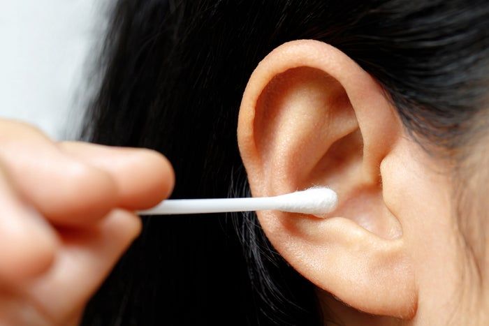 A person using a cotton swab to clean their ear