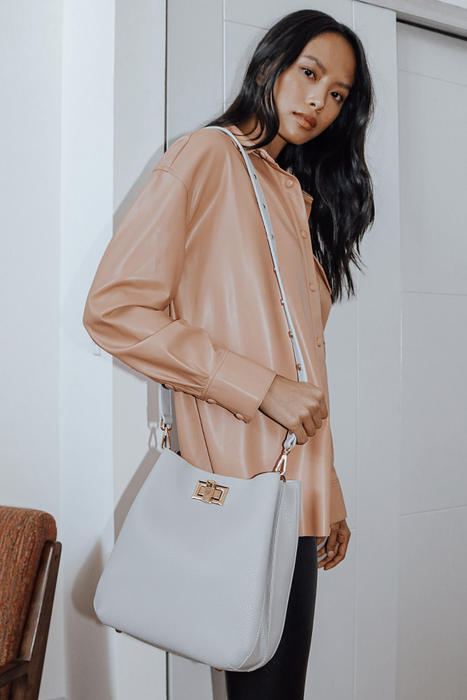 Model with a gray tote bag draped over her arm