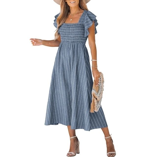 The model is seen wearing the dress while holding a tasseled clutch bag.