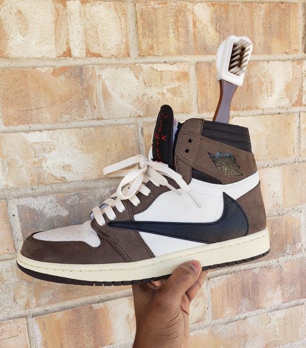 A reviewer holding their Travis Scott Jordan 1 sneakers alongside the suede brush