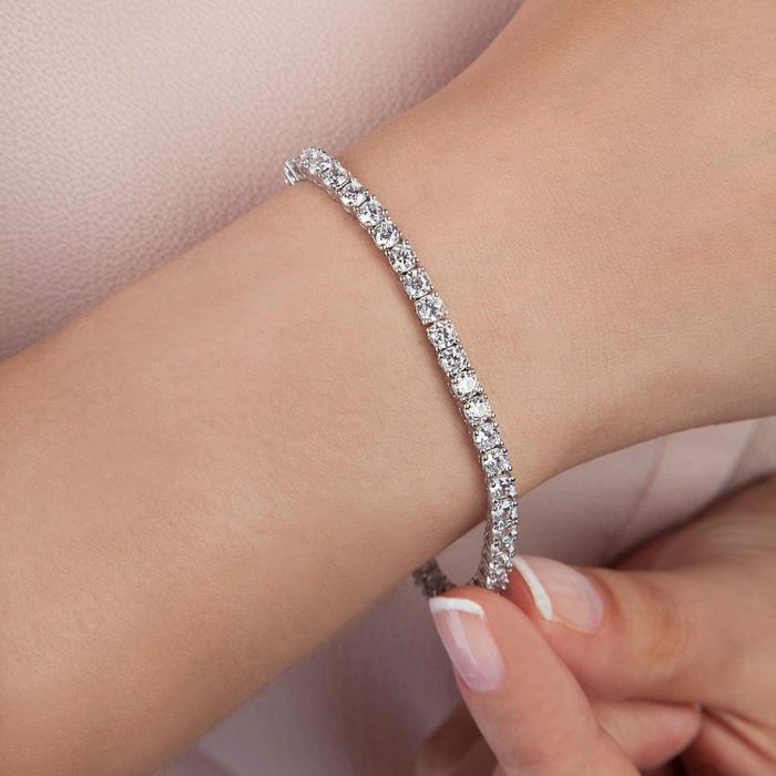 Close-up product image of a white gold tennis bracelet on a model’s arm