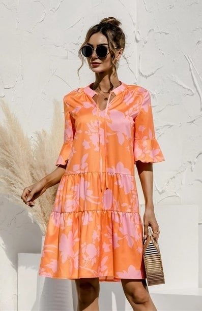 The model is wearing the dress and carrying a stylish striped handbag.