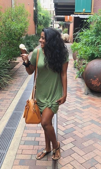 Reviewer is styled in a green T-shirt dress, paired with sandals and a tan bag