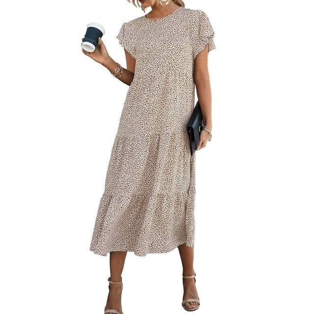 Model showcasing the dress in a small dotted print, accessorized with bracelets and strappy heels
