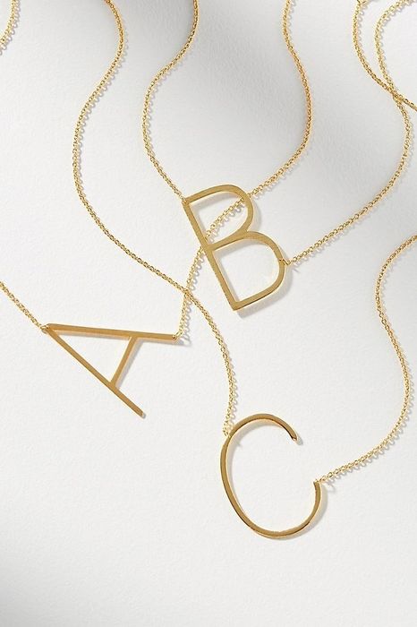 Three brass necklaces featuring the letters A, B, and C