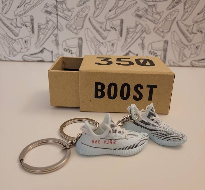Two Yeezy sneaker keychains accompanied by a miniature shoebox