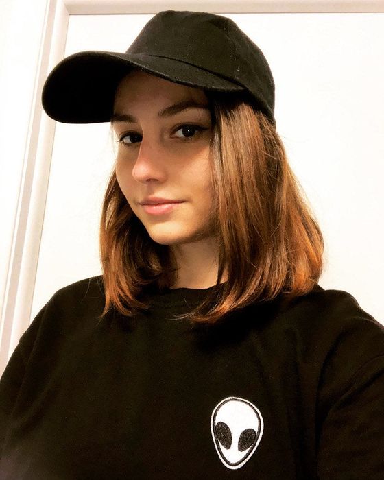 I’m wearing a black sweatshirt with an alien patch and a matching black baseball cap