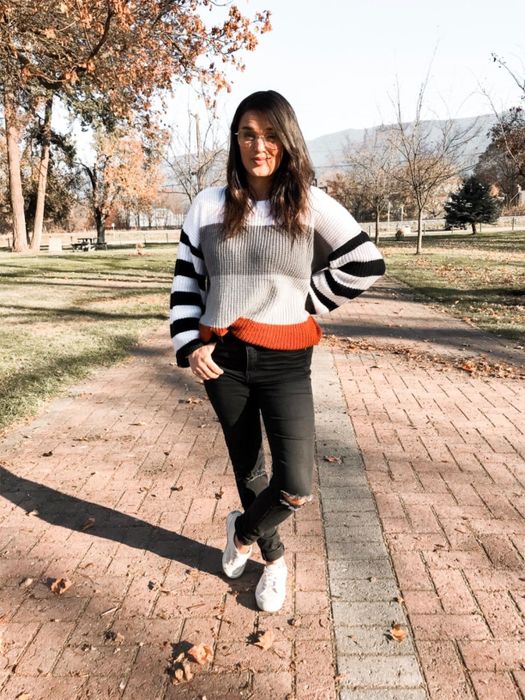 Reviewer wears the same sweater with black ripped jeans and white sneakers on a crisp autumn day