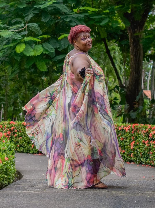 Reviewer in a flowy, floral dress striking a pose on a garden path