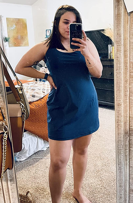 a reviewer wearing the sleeveless navy blue dress