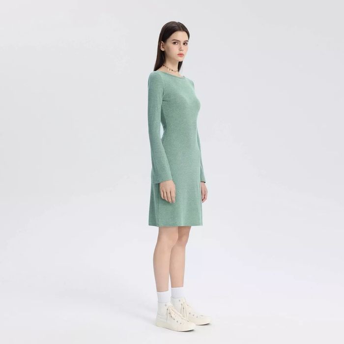 A model wearing a simple, long-sleeve dress paired with sneakers.