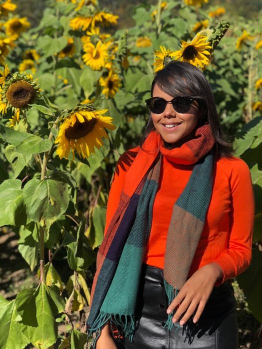 Reviewer is seen wearing a color-block scarf with a bright red turtleneck and a black skirt