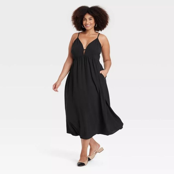 The model wears a sleek black sleeveless dress featuring spaghetti straps.