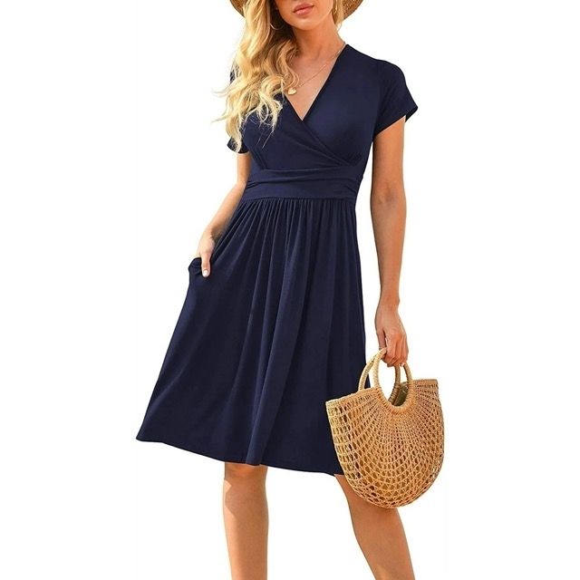 Model wearing the dress and carrying a woven handbag, topped off with a straw hat