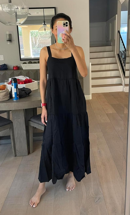 Person in a long, sleeveless black dress taking a mirror selfie