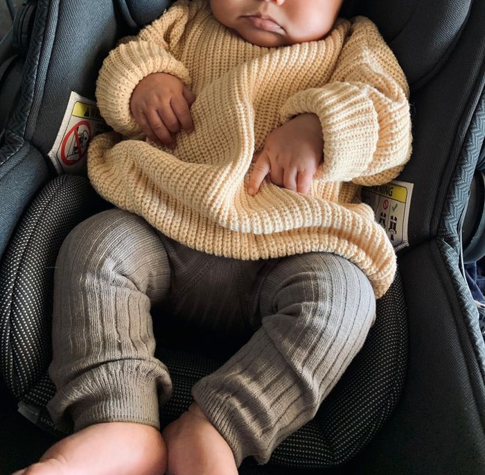 A reviewer’s baby dressed in a stylish tan oversized sweater