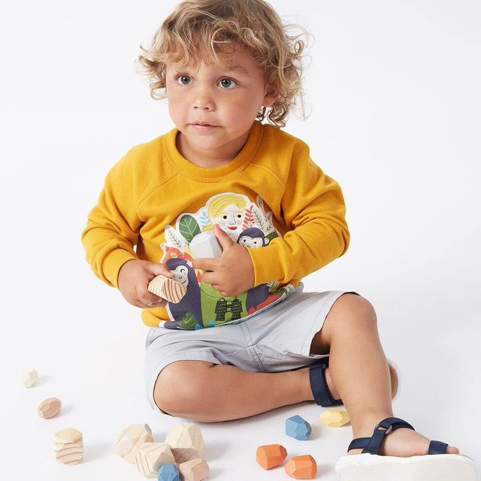 A child wearing a vibrant yellow sweatshirt featuring Jane Goodall and monkeys embroidered on it