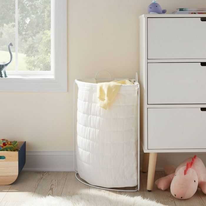 a white laundry hamper placed in a corner