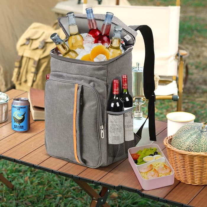 An insulated backpack cooler filled with drinks and food, placed on a table during an outdoor picnic. Ideal for keeping refreshments handy on the go.