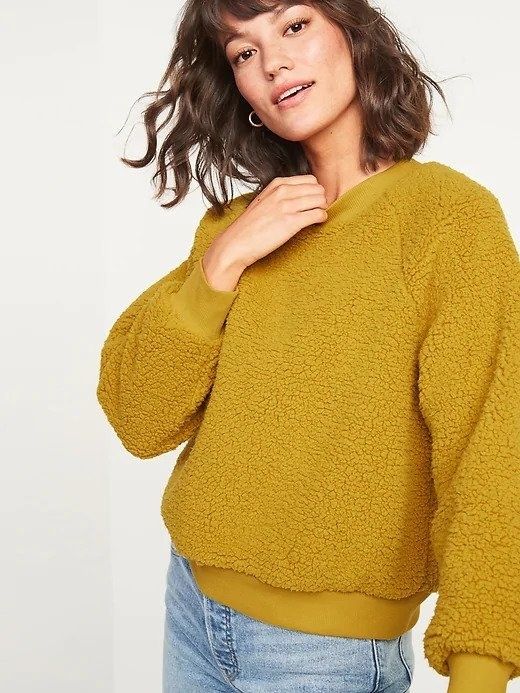 A woman wearing a dark yellow sherpa sweatshirt.