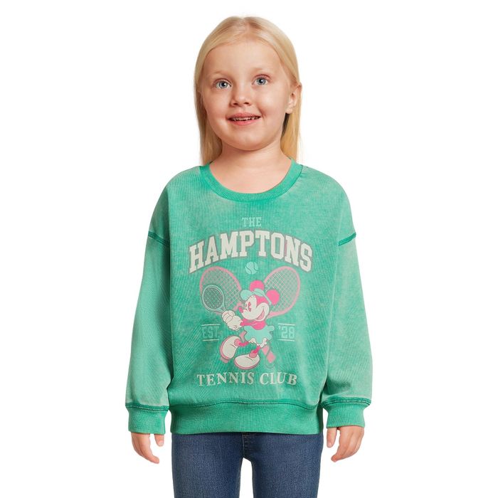 A child wearing a green sweatshirt with Minnie Mouse on it, playing tennis