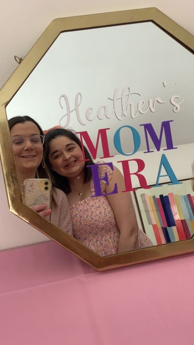 Two friends taking a selfie in a mirror with the text 